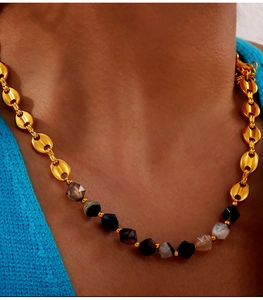 Macro detail of 18K gold plated beaded necklace with faceted natural stones on a model