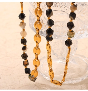 Detail of 18K gold plated chain with faceted natural stones on a glass display