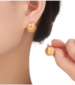 Détail de boucles d'oreilles dorées 18K avec texture géométrique et relief d'étoile