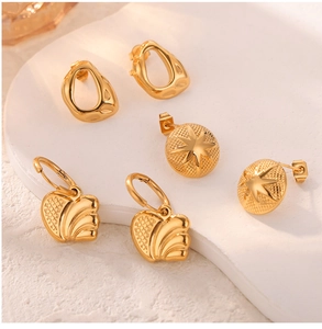 Gros plan de boucles d'oreilles géométriques dorées à l'or 18 carats sur fond de pierre