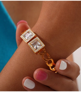 Dettaglio di un bracciale a catena cubana dorato con due cristalli quadrati e diamanti