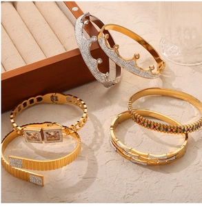 Dettagli di bracciali dorati vintage francesi e bracciali corona con strass su sfondo pietra