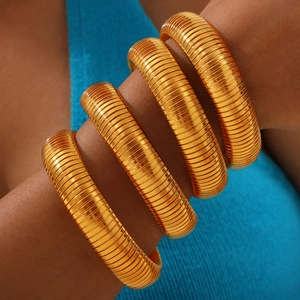 Chic gold-plated flexible tubogas bracelets stacked on arm with luxury textured finish