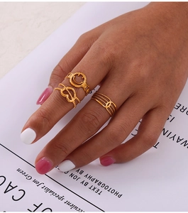 Close-up of three gold-plated titanium steel rings featuring hollow heart and smiley faces