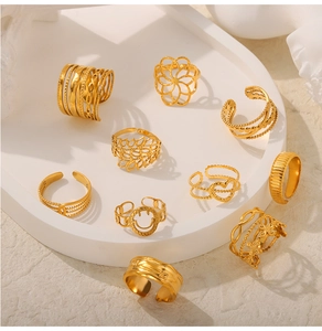 Detailed arrangement of ten gold textured geometric and floral rings on a white stone base