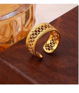 Detailed shot of a gold-plated titanium open ring with hollow woven wave design on wood