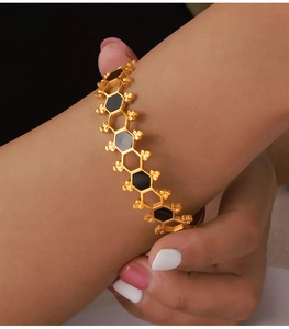 Dettaglio di un bracciale esagonale geometrico con smalto nero indossato su un polso