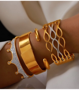 Detail of 18k gold plated crown and hollow diamond bangles set on woman's wrist