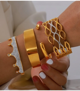 Detail of layered gold-plated crown and wave bangles with sparkling zircon accents