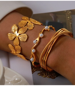 Detail of gold-plated titanium bangles with floral texture and white pearl accents