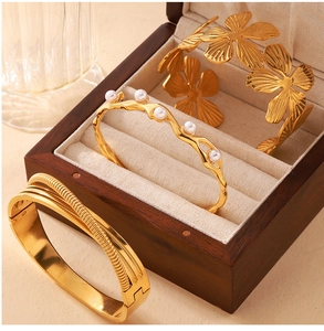 Detail of gold-plated titanium steel bracelet with shell pearls and floral textures