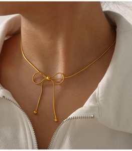 Macro view of golden stainless steel butterfly bow necklace with dangling fringe detail