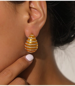 Detail of teardrop gold earrings with layered pavé diamonds on model ear
