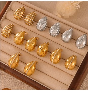 Close-up of teardrop earrings in gold and silver with rhinestones in a velvet tray