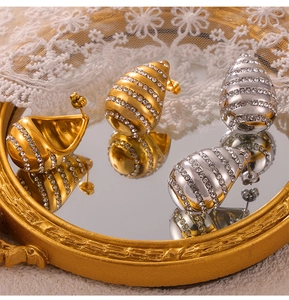 Detailed shot of gold and silver teardrop stud earrings with pave crystals on a vintage tray