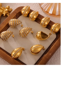 Detailed macro view of gold-plated teardrop earrings with crystals and shell texture