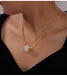 Gros plan d'un collier plaqué or avec un pendentif boule orné de cristaux étincelants