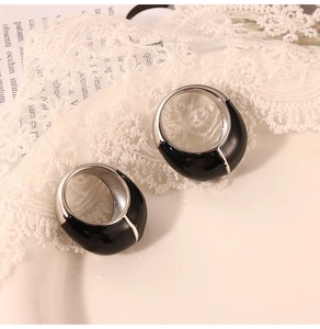 Détail de bagues en titane avec finition émail noir sur tissu en dentelle blanche