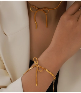 Dettaglio del set girocollo e bracciale a fiocco dorato con trama a catena di serpente