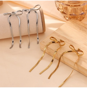Dettaglio ravvicinato di orecchini a fiocco oro e argento con lunghe nappe a catena