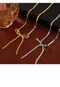 Dettaglio della collana catena serpente con fiocco in oro e argento su seta rossa