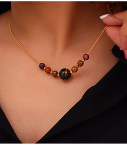 Detailed view of handmade titanium necklace with tiger eye stone beads and gold chain