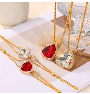 Detail eines Vintage-Schmucksets aus Gold mit roten und klaren Steinen auf Kordelketten