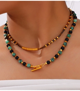 Detail of layered titanium steel necklace with natural stones and gold toggle clasp