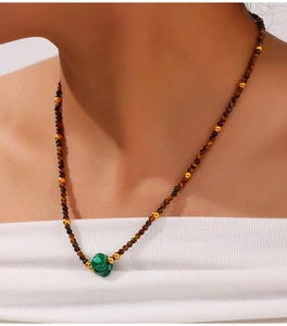 Detail of beaded necklace with tiger eye stones and green malachite on a female model