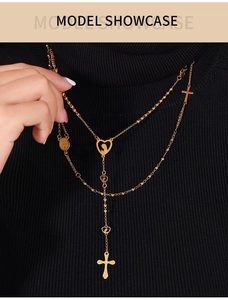 Vista de detalle de collar dorado en Y con colgantes de cruz y corazón sagrado