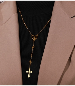 Detalle de collar en Y dorado con medalla corazón de Virgen María y colgante de cruz