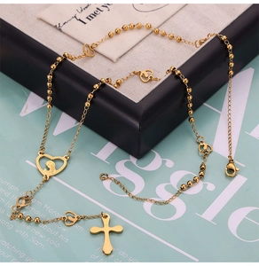 Detalle de collar de cuentas doradas con cruz y colgante de corazón de la Virgen