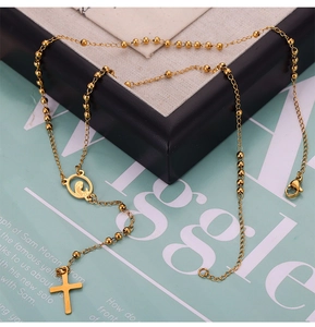 Detalle de collar de cuentas doradas con un medallón religioso y un colgante de cruz
