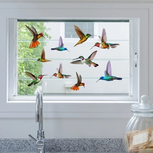 Detailed view of ten colorful hummingbird window clings on a clear glass window surface