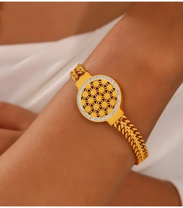 Détail d'un bracelet doré avec pendentif géométrique ajouré et strass blancs brillants