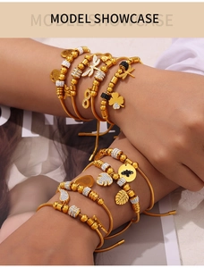 Detail of layered gold dragonfly and clover charms on snake chain bracelet sets
