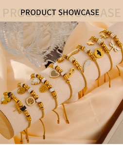 Detail of gold-plated bracelets with heart and butterfly charms on a velvet display stand
