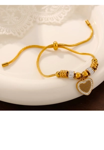 Detail of gold-plated snake chain bracelet featuring a crystal heart pendant and slide clasp