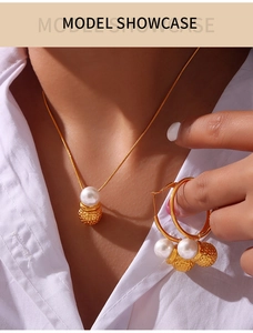 Close-up of model wearing pearl necklace and matching hoop earrings set in golden finish