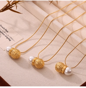 Macro detail of French vintage gold snake chain necklaces with pearls and hammered balls