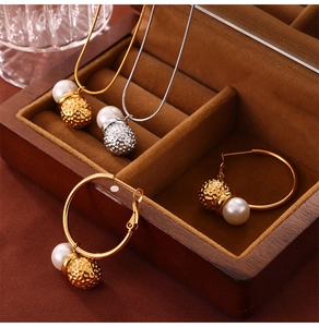 Detail of gold and silver jewelry set with pearls and hammered metal balls in a wooden box