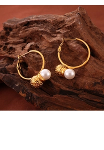 Detailed close-up of golden hoop earrings with hammered metal balls and white pearls