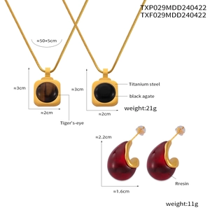 Détail de colliers en acier titane avec œil de tigre, onyx et boucles d'oreilles rouges