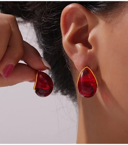 Gros plan de boucles d'oreilles goutte avec résine rouge foncé et monture dorée chic