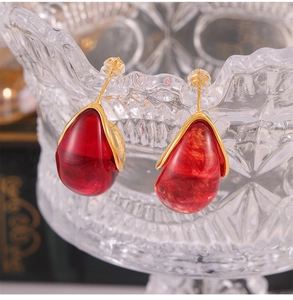 Gros plan détaillé de boucles d'oreilles vintage dorées avec pendentifs en résine rouge