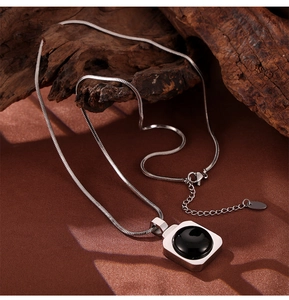 Gros plan d'un collier en acier titane avec pendentif en pierre noire sur bois