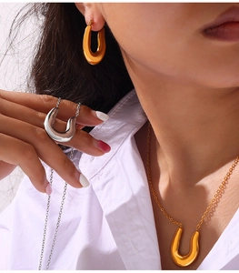 Close-up of elegant gold and silver U-shaped jewelry set on a white shirt model