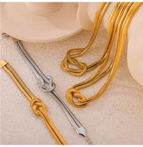 Detailed close-up of gold and silver snake chain necklace with a woven knot design
