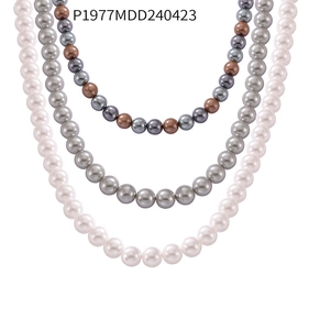 Macro shot of three high-luster round shell pearl necklaces in white, grey, and brown hues
