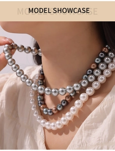 Close-up of multi-layer necklace with white, grey, and bronze round pearls on a model